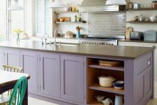 a stylish modern kitchen with white cabinets and a purple kitchen island plus stone countertops and white pendant lamps