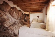 02 The bedroom features a fantastic rock formation and neutral decor and wood