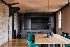 02 The kitchen and dining room are united, they feature exposed brick, blackened metal and stone and emerald velvet chairs soften the look