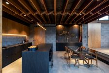 03 The kitchen is done with concrete, light stained and matte black furniture, a black kitchen island and the dining space features a beautiful glass table