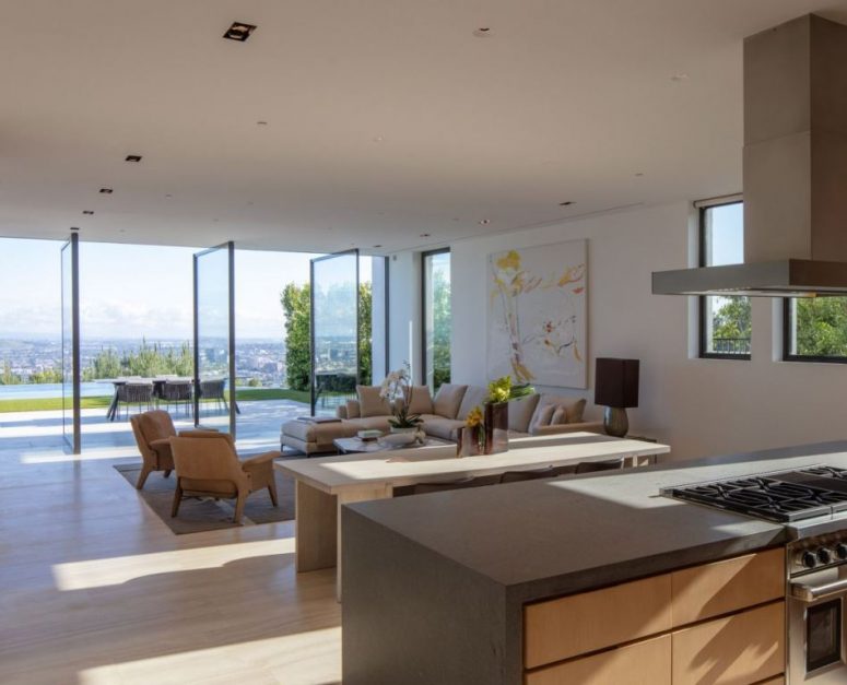 The living room is done with pivot glass doors that help the space to merge with outdoors