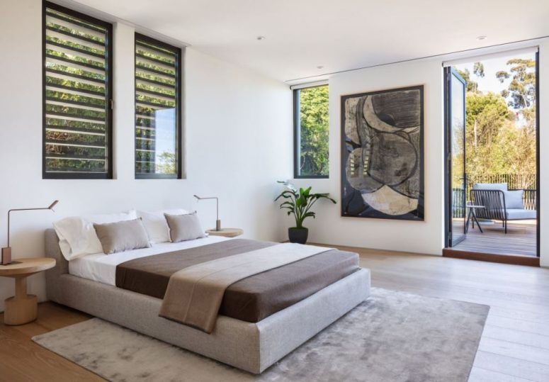 The bedroom is done in a neutral color scheme, with a statement artwork and there's an access to outdoors