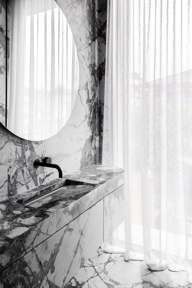 The powder room continues the idea with white marble all over and elegant minimalist decor