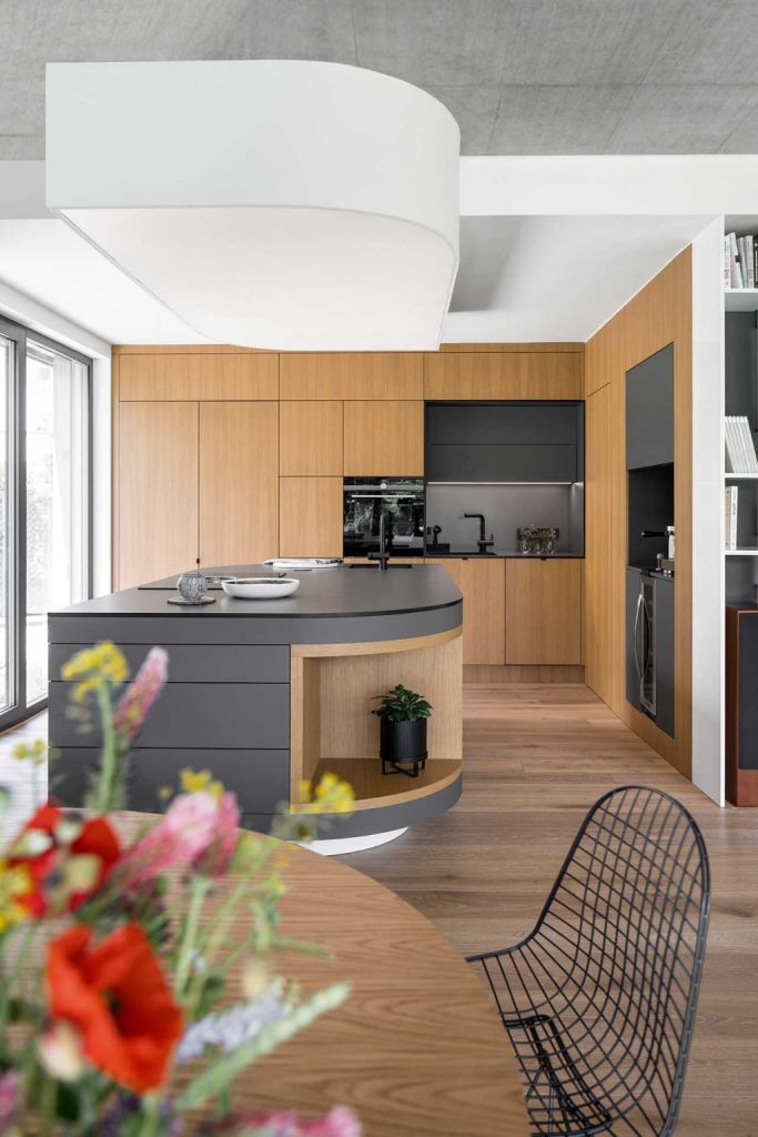 The kitchen is done with sleek cabinets and surfaces, with a concrete tabletop and a backsplash