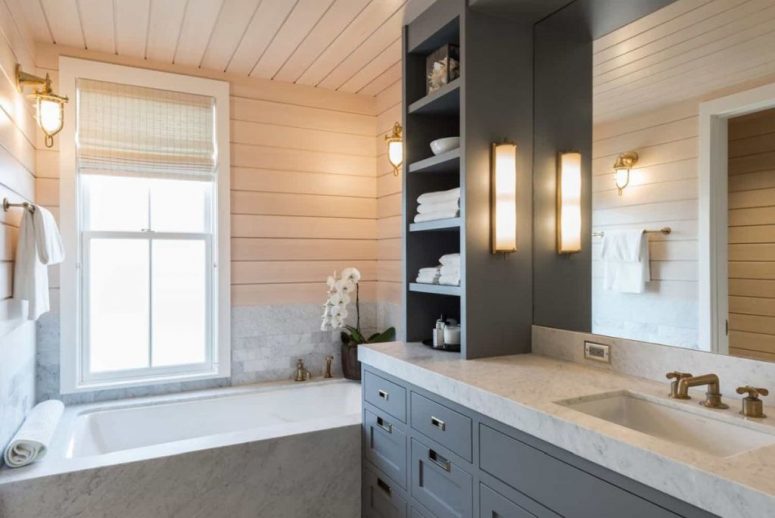 There's a large grey vanity and a bathtub clad with white marble