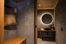 09 The bathroom continues the decor theme with concrete walls and floors, a lit up mirror and neutral stained wood