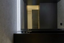 09 The bathroom is minimalist, with a black floating vanity, a mirror wall and built-in lights