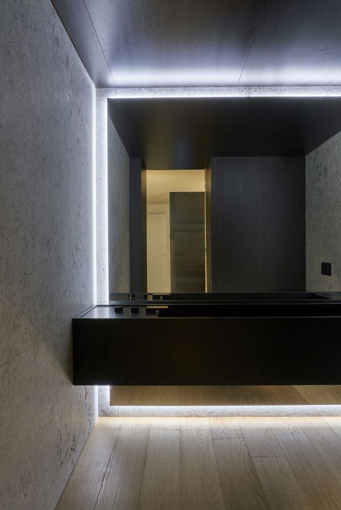 The bathroom is minimalist, with a black floating vanity, a mirror wall and built in lights