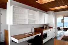 10 The kitchen shows off stained and white wooden cabinetry, a small working space with a floating desk