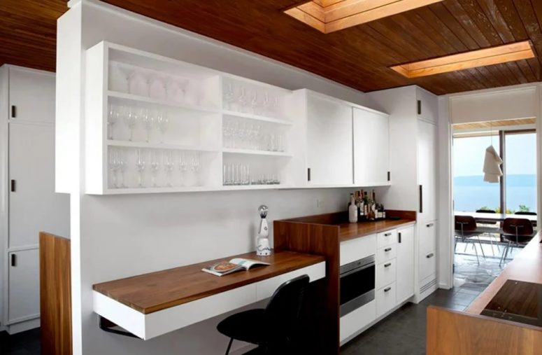 The kitchen shows off stained and white wooden cabinetry, a small working space with a floating desk