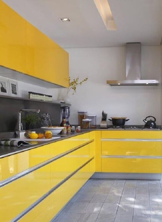 a bold minimalist kitchen with sleek yellow cabinets, a grey matte backsplash and countertops and stainless steel appliances