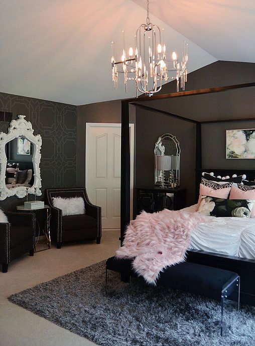 a chic and refined bedroom with black walls, a black bed and other sitting furniture, a catchy crystal chandelier and pink bedding
