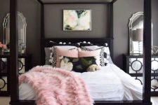 a chic grey bedroom with black furniture, mirrored nightstands, blush and black bedding and layered rugs