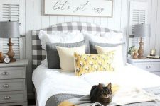 a cozy farmhouse bedroom with a grey plaid bed, dove grey nightstands and lamps, grey and yellow bedding
