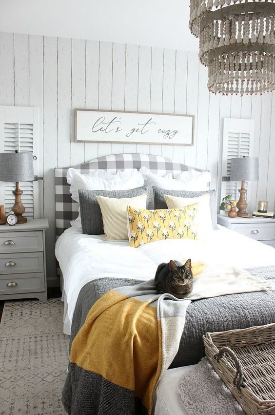 a cozy farmhouse bedroom with a grey plaid bed, dove grey nightstands and lamps, grey and yellow bedding