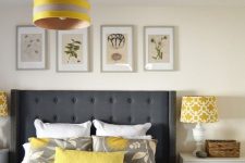 a modern bedroom in off-white and creamy, with a graphite grey bed, touches of yellow and a botanical gallery wall