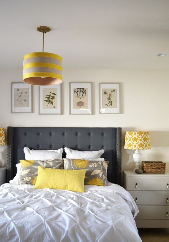 A modern bedroom in off white and creamy, with a graphite grey bed, touches of yellow and a botanical gallery wall