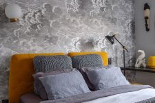 a small bedroom with a grey cloud wallpaper wall, a mustard upholstered bed and accessories, grey and white bedding