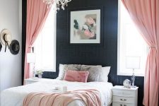 an elegant bedroom with black printed wallpaper, refined white furniture, pink textiles and a crystal chandelier