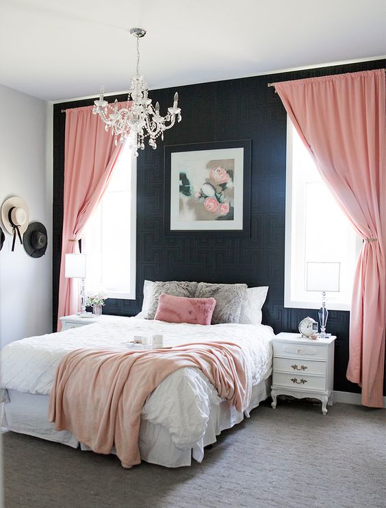 an elegant bedroom with black printed wallpaper, refined white furniture, pink textiles and a crystal chandelier