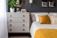 an elegant mid-century modern bedroom with graphite grey walls, neutral furniture, shiny and bright touches and yellow and white bedding