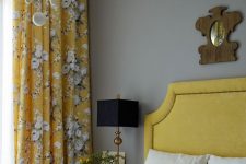 an elegant vintage-inspired bedroom with light grey walls, a mustard bed, mustard floral curtains, a chic chandelier and grey and mustard bedding