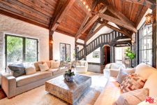 02 This barn living room is done with a wooden ceiling and beams, chic furniture and stone walls