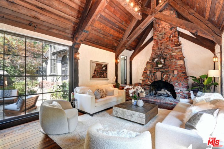 There's a large fireplace, a glazed wall and a mini wooden table