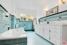 05 The bathroom is done with light blue tiles, a bathtub clad with tiles and a white vanity