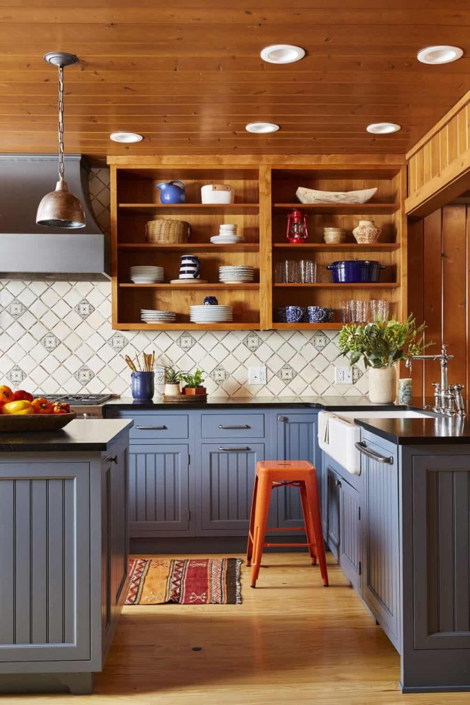 The kitchen is done in blues, with stained wooden shelving instead of upper cabinets and metal stools and lamps