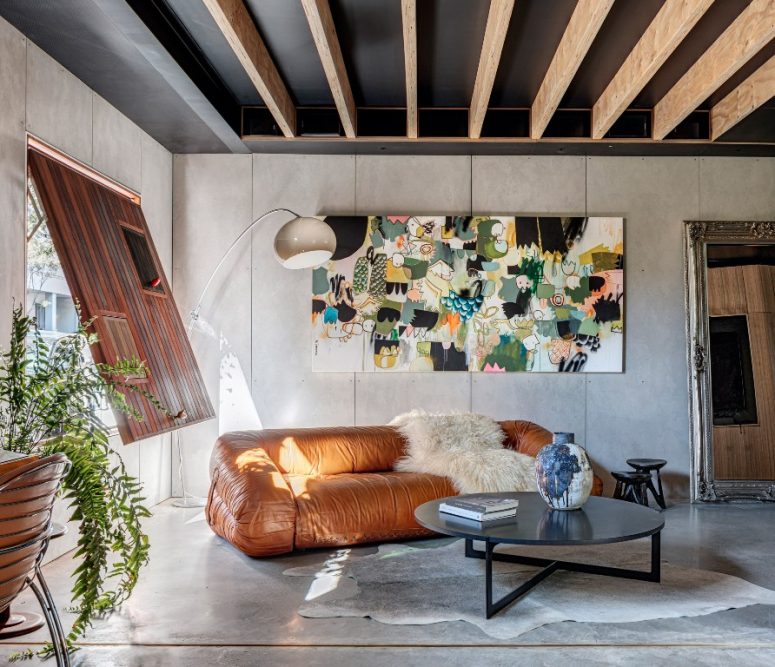 The living room shows off a unique artwork, a leather sofa and a wooden shutter with mini windows
