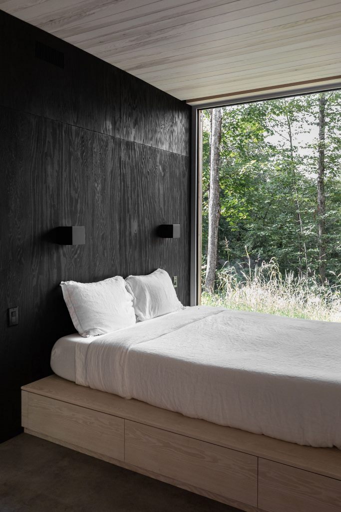 The bedroom is done with black walls, a platform bed with storage and a glazed wall