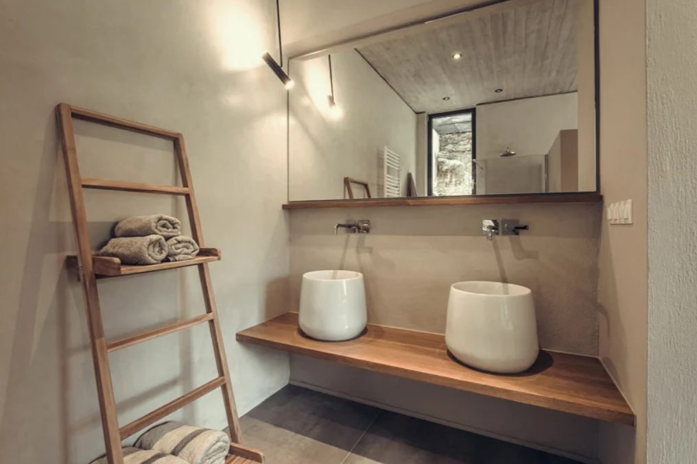 The bathroom features a floating vanity, two catchy sinks and some shelves