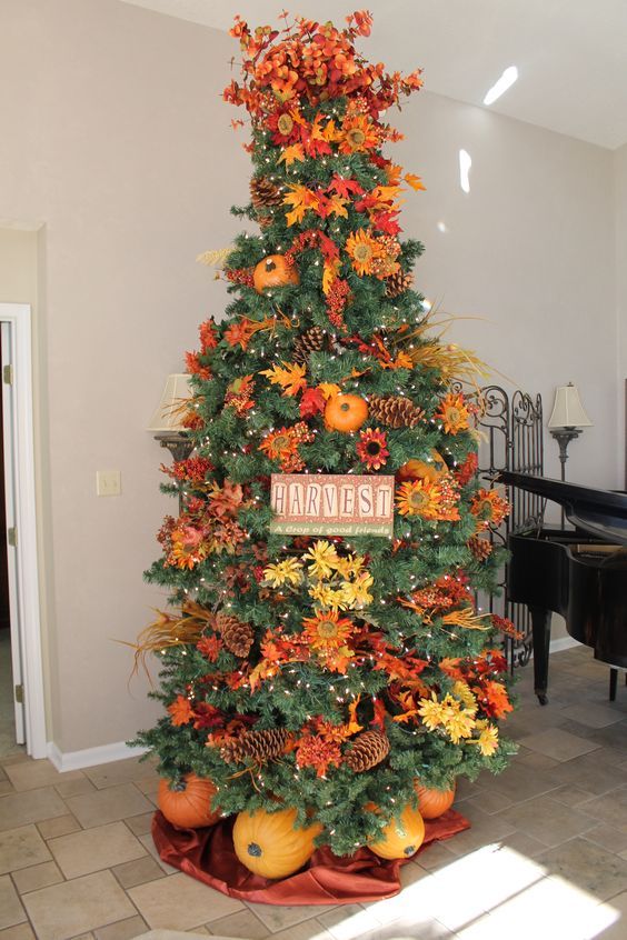 a gorgeous and bright Thanksgiving tree with lights, pinecones, bright faux blooms and leaves, branches, a sign and pumpkins