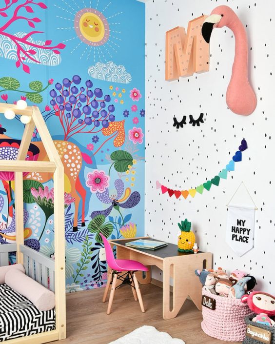a beautiful and bold kid's room with a bright paitned wall, faux taxidermy, bold garlands and toys and a hot pink chair