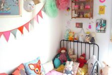 a bold kid’s room with colorful art, accessories and toys, colorful bedding, pompoms and garlands