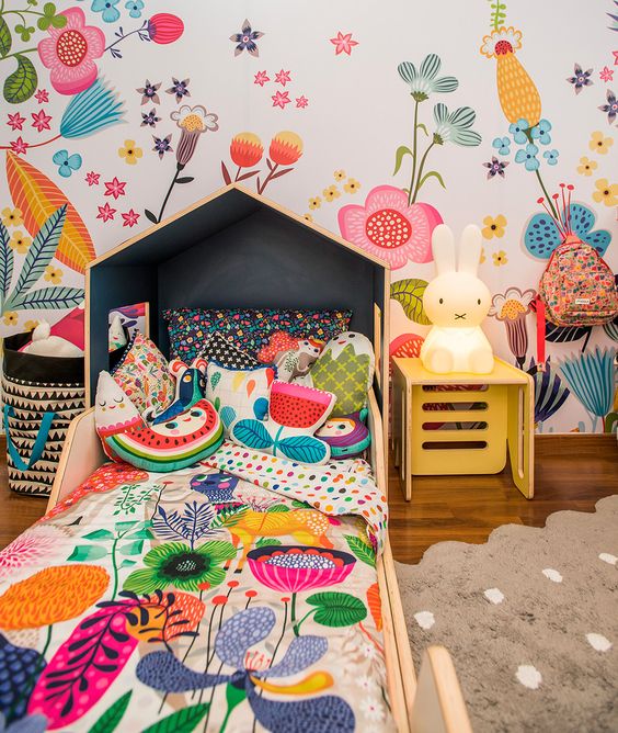 a bright and fun kid's room with a floral wall, matching floral bedding, fruit and flower pillows and a Miffy lamp