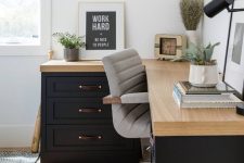 a chic modern working space with a black corner desk, a grey chair, some potted plants and a black table lamp