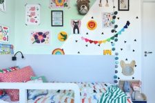 a colorful and fun kid’s room with a color block wall, bright decor and garlands, colorful bedding and linens and bold toys