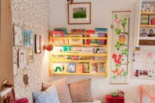 a colorful kid’s room with a wallpaper wall, a yellow shelf, bright artworks and bedding and colorful toys