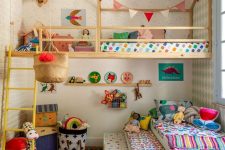 a colorful kid’s room with bright bedding, rugs, pillows and blankets and pastel pendant lamps