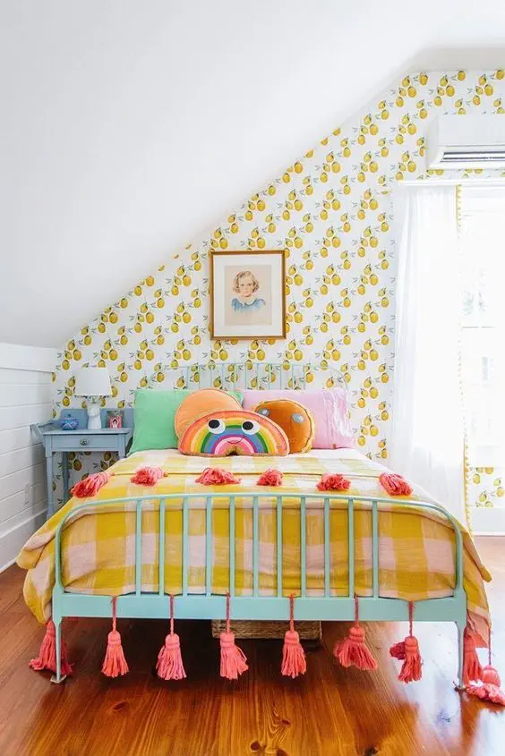 a colorful kid's room with retro fruit print wallpaper, colorful bedding, artworks, tassels and a blue nightstand