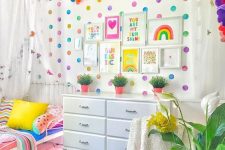 a colorful kid’s space with a polka dot wall, a bold garland, bright bedding and fruit pillows and a bold rug just wows
