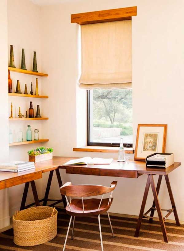 a cozy rustic home office nook with a large trestle corner desk, open shelves, a basket and a wooden chair plus shades