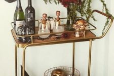 a glam Halloween bar cart with a floral centerpiece, gilded and copper skulls, pumpkins and greenery is easy and chic