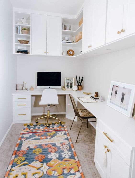 A mid century modern home office in white, with a corner desk and cabinets in it, cabinets over the desk and a bright and fun rug
