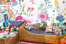 a shared colorful kid’s room with a bright floral wall and bold bedding, a bold striped rug and books on the bookshelves