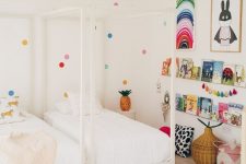 a shared kid’s room done in neutrals but spruced up with brights – polka dots on the wall, colorful art, garlands and books