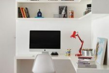 a small white working nook with a corner desk and a box corner shelf, a chair and a stool, a red table lamp and some decor