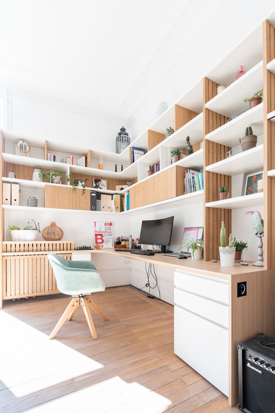 A stylish Scandinavian home office with customized storage furniture and a built in desk, a green chair, decor and books is amazing